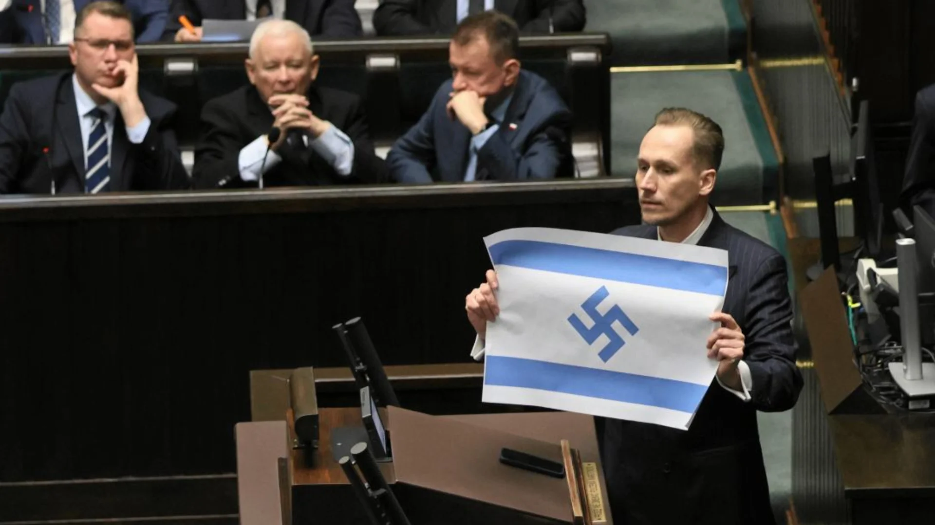 O deputado da direita polonesa, Konrad Berkowicz, ergue no Sejm uma bandeira de Israel na qual a Estrela de Davi foi substituída por uma suástica. Foto: IMAGO/Eastnews