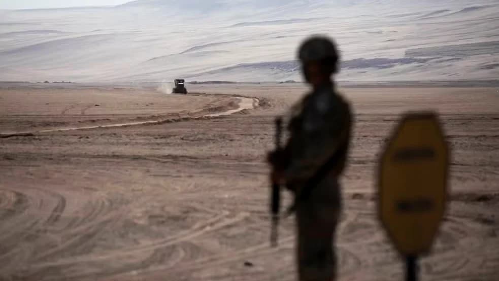 Um soldado faz guarda enquanto máquinas pesadas operam perto do posto fronteiriço de Chacalluta, na fronteira entre Chile e Peru, em 16 de março de 2026