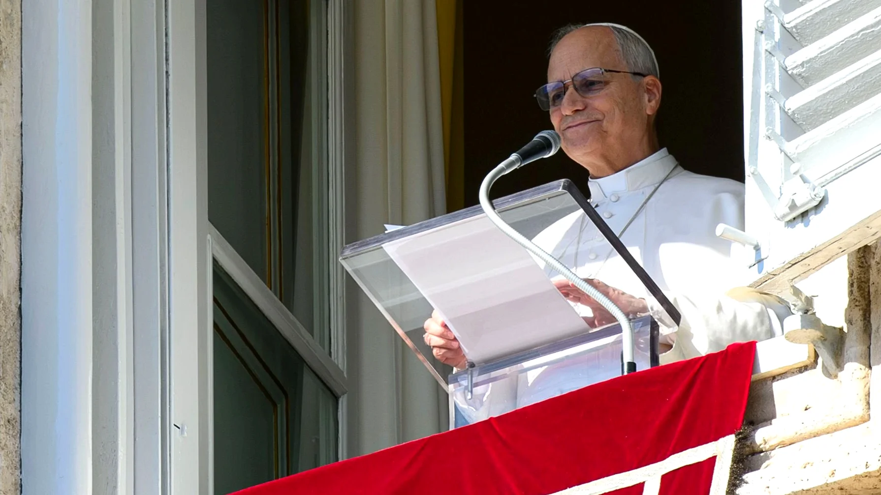 apa Leão XIV na janela do Palácio Apostólico, no Vaticano, durante a audiência de domingo. O pontífice aparece sorrindo levemente atrás de um ambão de vidro, no momento em que enviou mensagens de apoio às vítimas das chuvas em Minas Gerais.