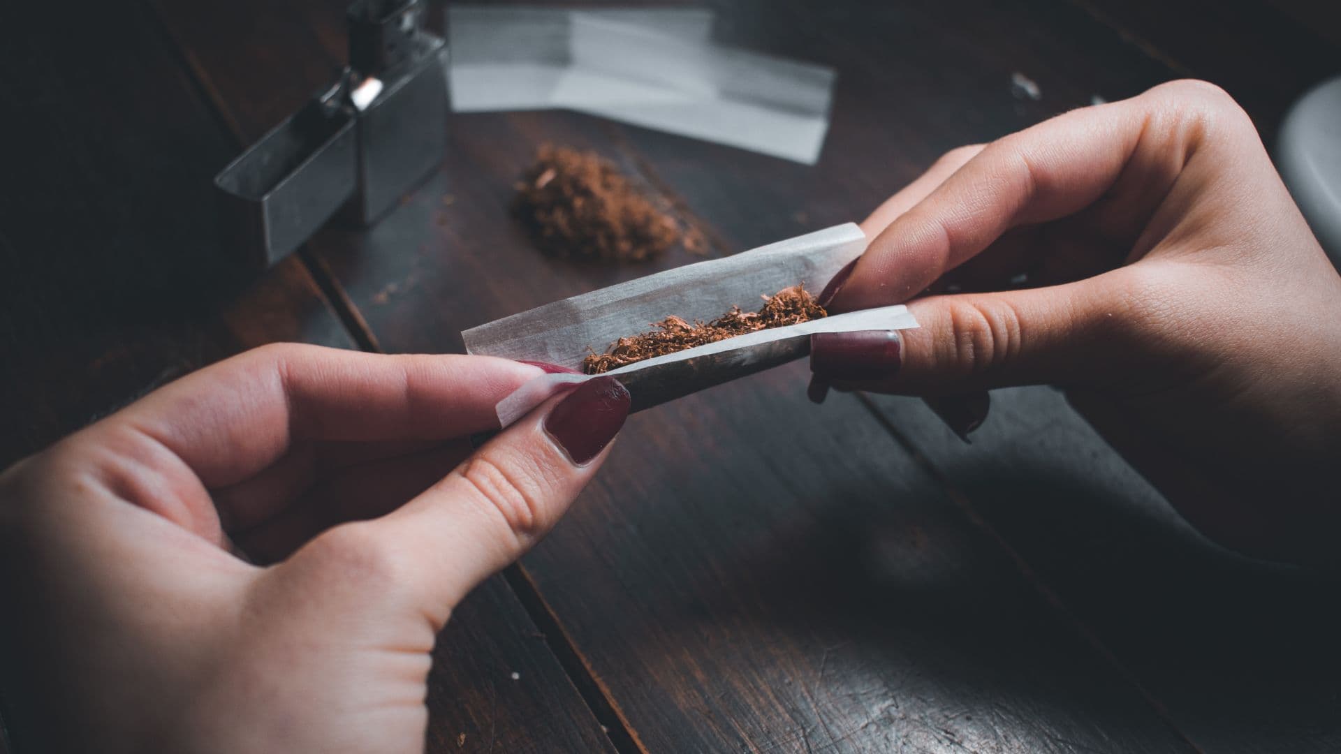 Pessoa aparece enrolando papelote de maconha