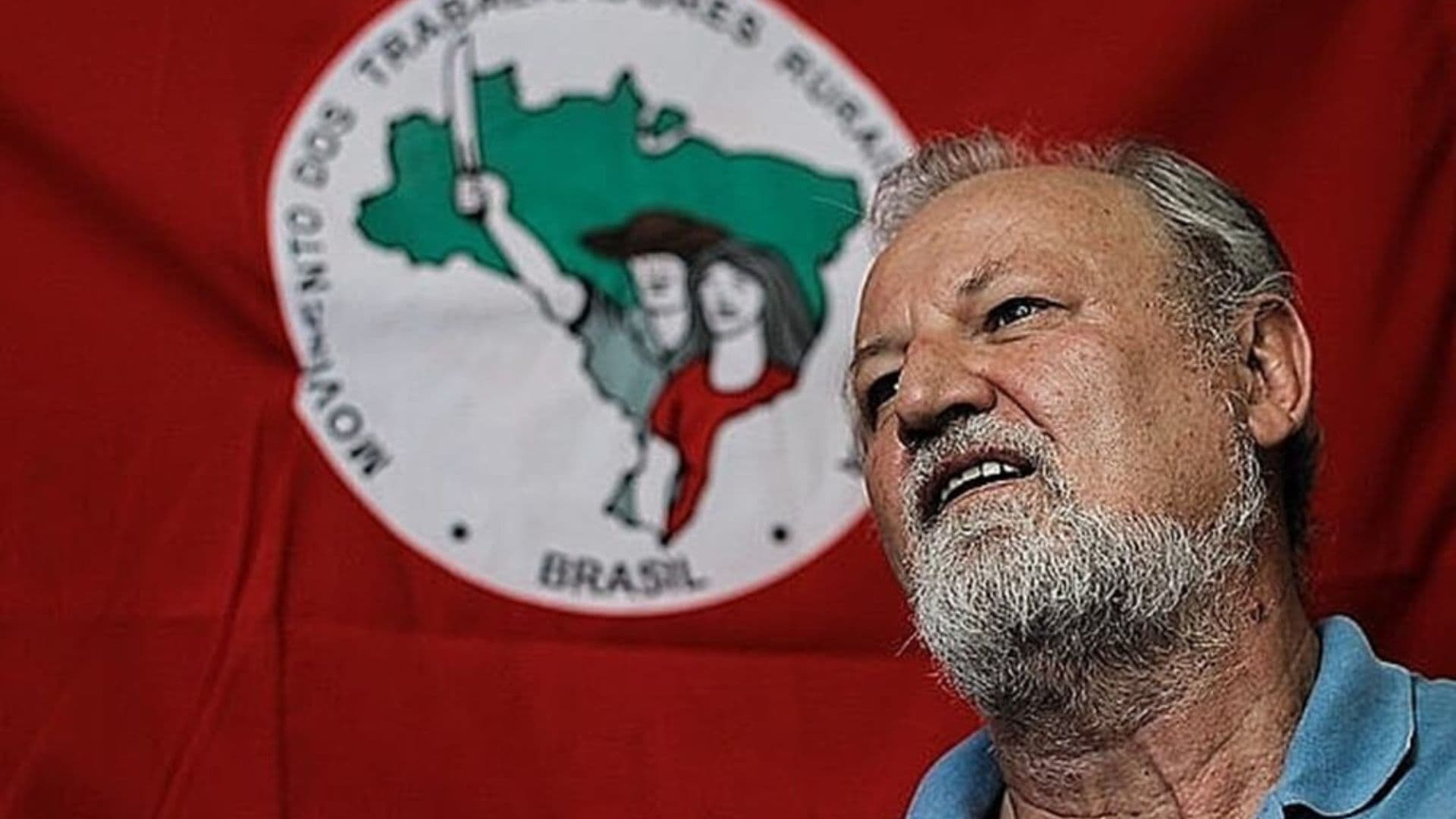 João Pedro Stédile em frente a uma bandeira do MST