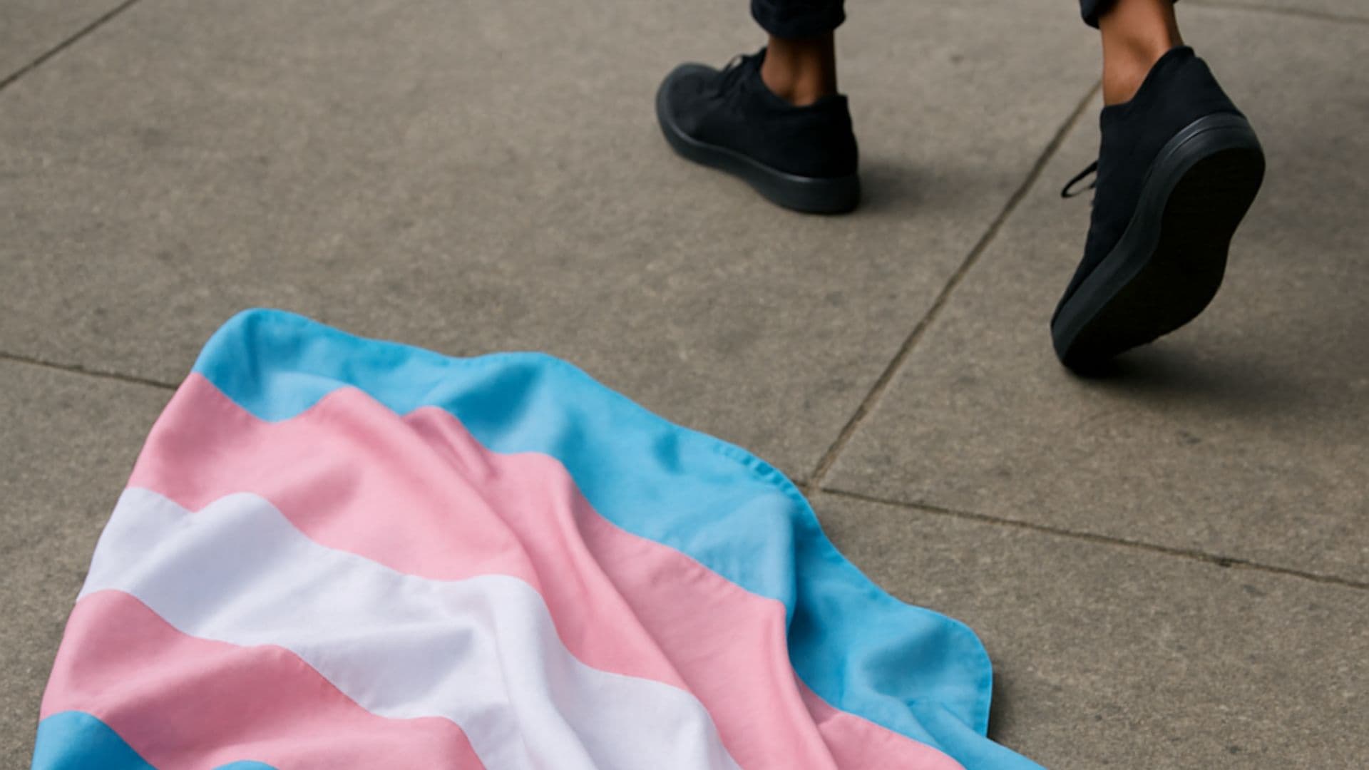 Pessoa caminhando para longe de uma bandeira trans no chão, dando a ideia de que a pessoa deixou o movimento.