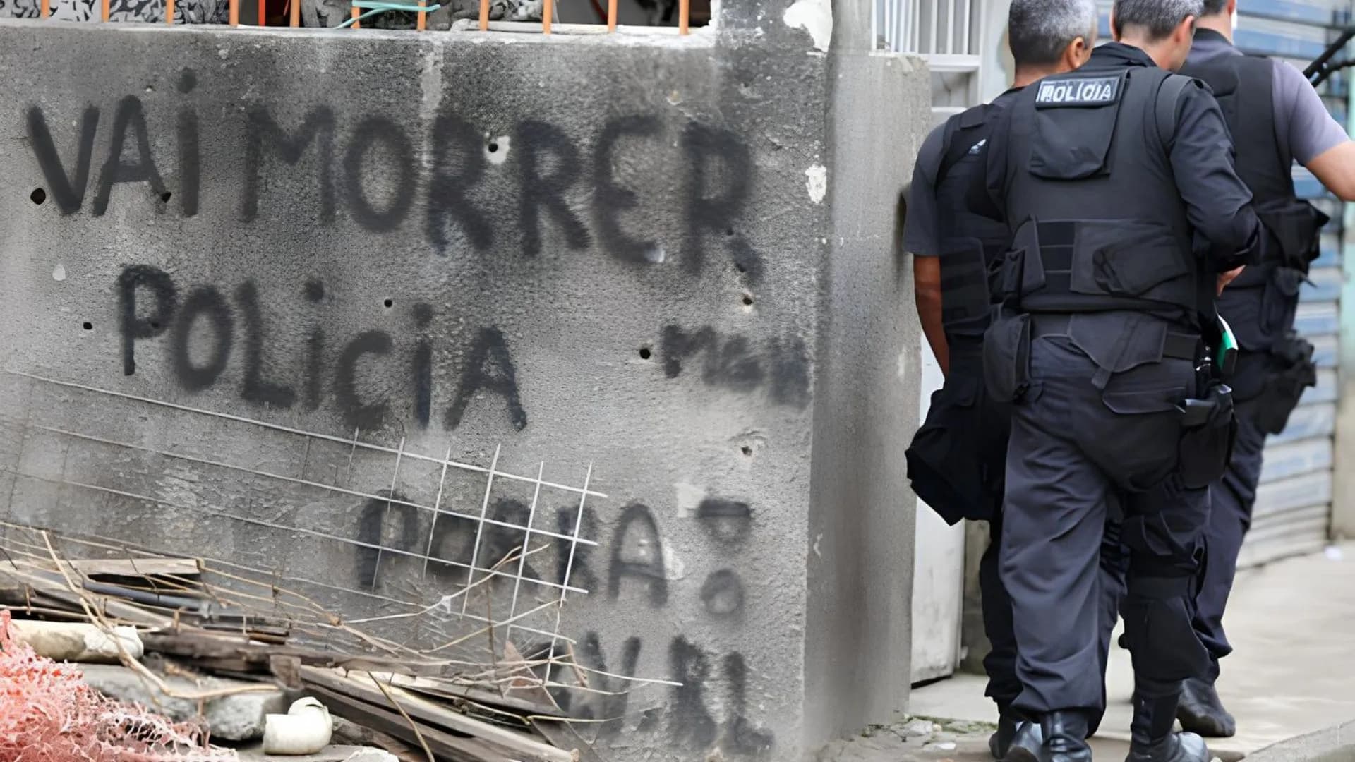 Policiais ao lado de uma pixação: "Vai morrer polícia"