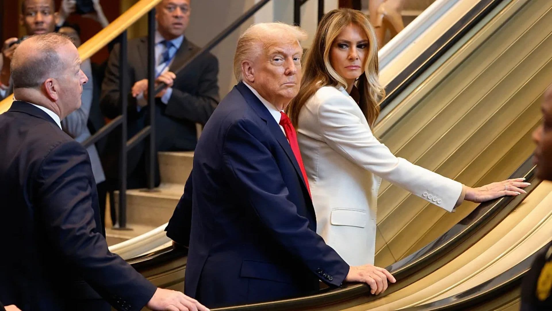 Presidente Trump e a Melania Trump na escada, olhando pra câmera